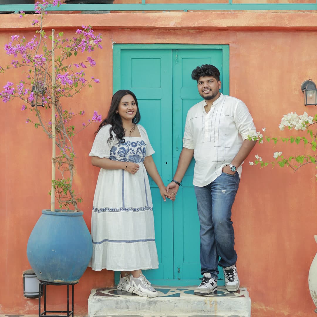 Couple standing on an outdoor patio beside teal wooden shutters