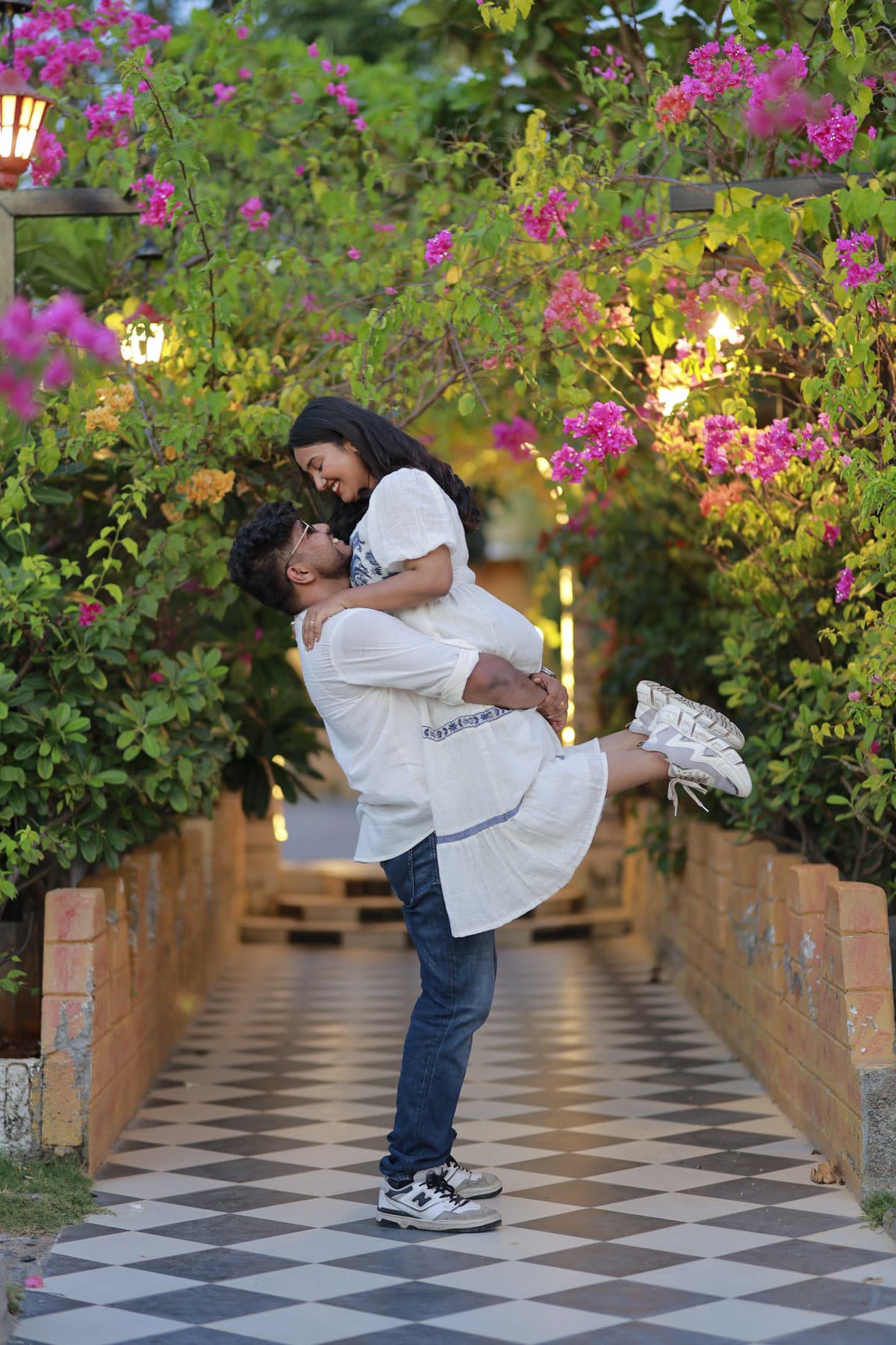 Couple embracing on an outdoor stone pathway lined with bougainvillea