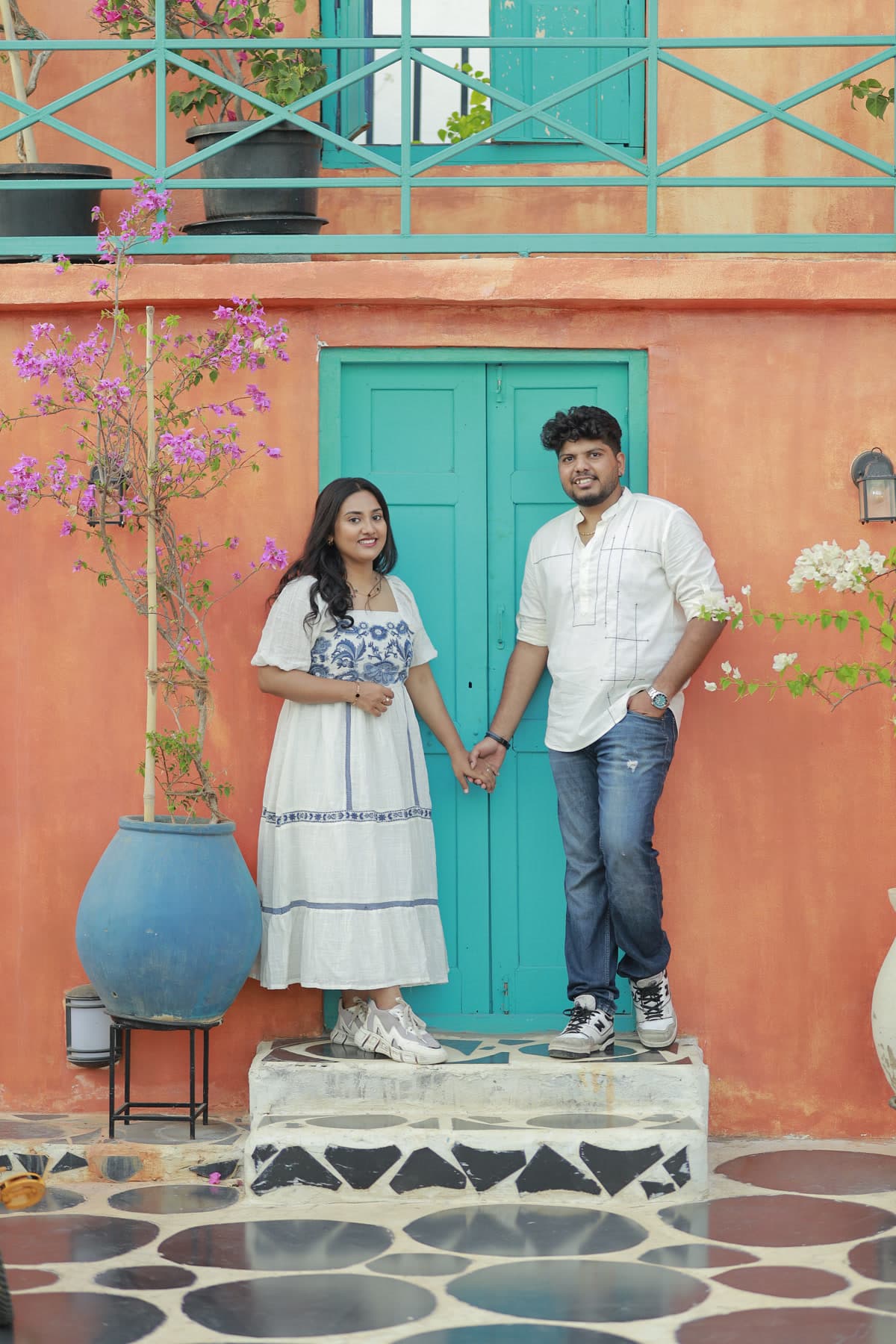 Couple standing on an outdoor patio beside teal wooden shutters
