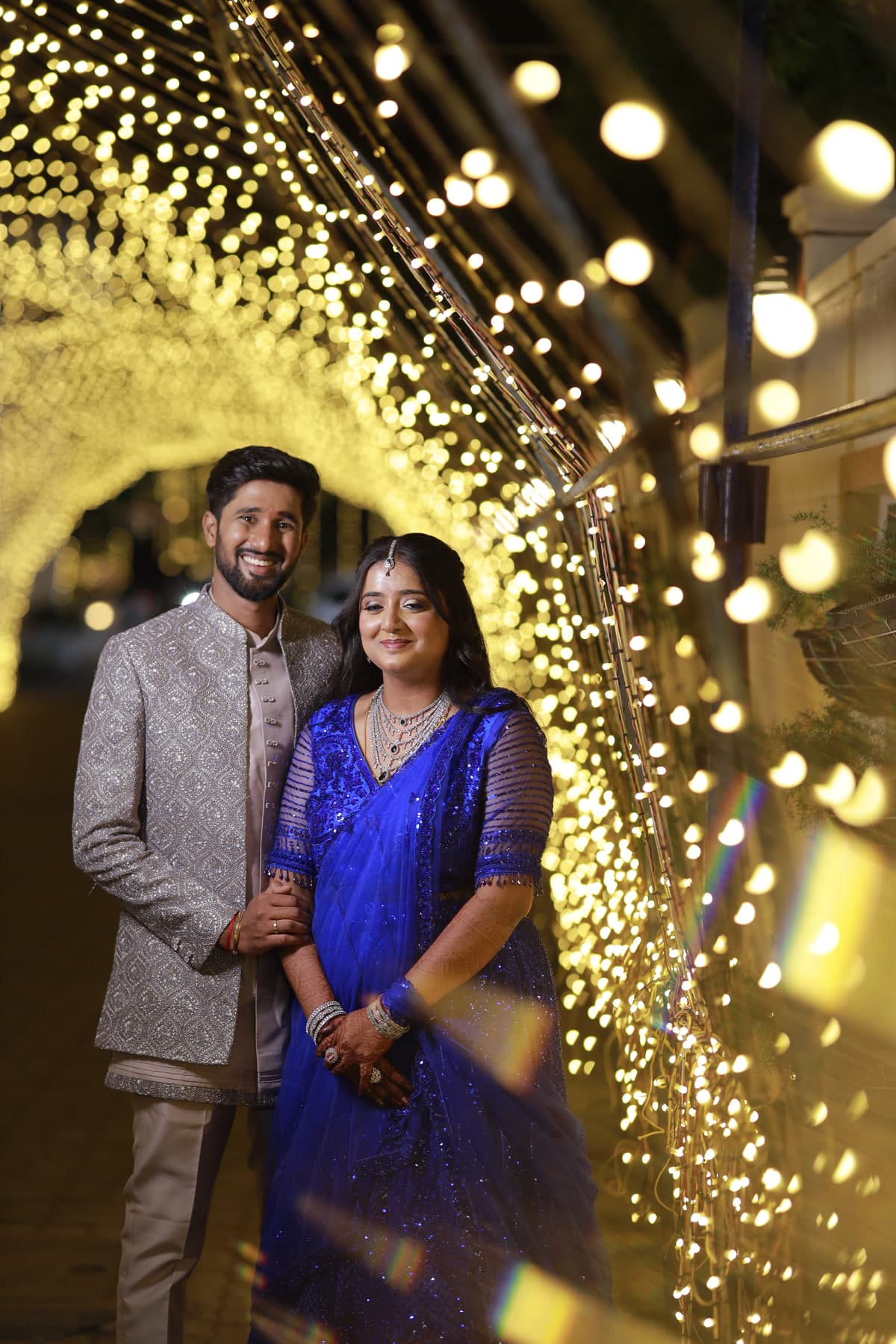 Couple standing in a golden fairy light tunnel