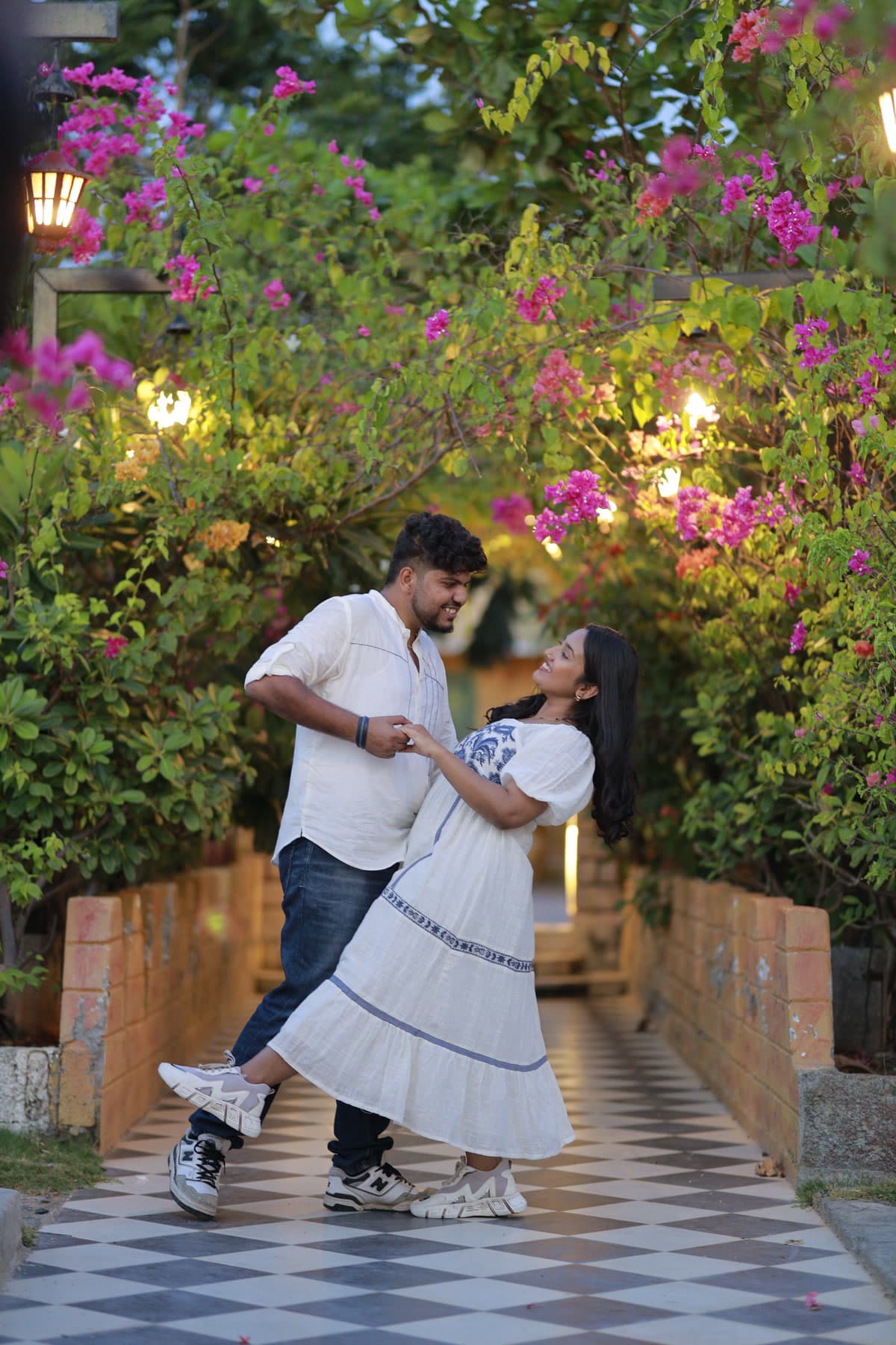 Couple walking along an outdoor pathway beneath pink flowering vines
